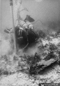 Plongeur dégageant un fragment de la coque au moyen de la suceuse (© Archives Drassm)